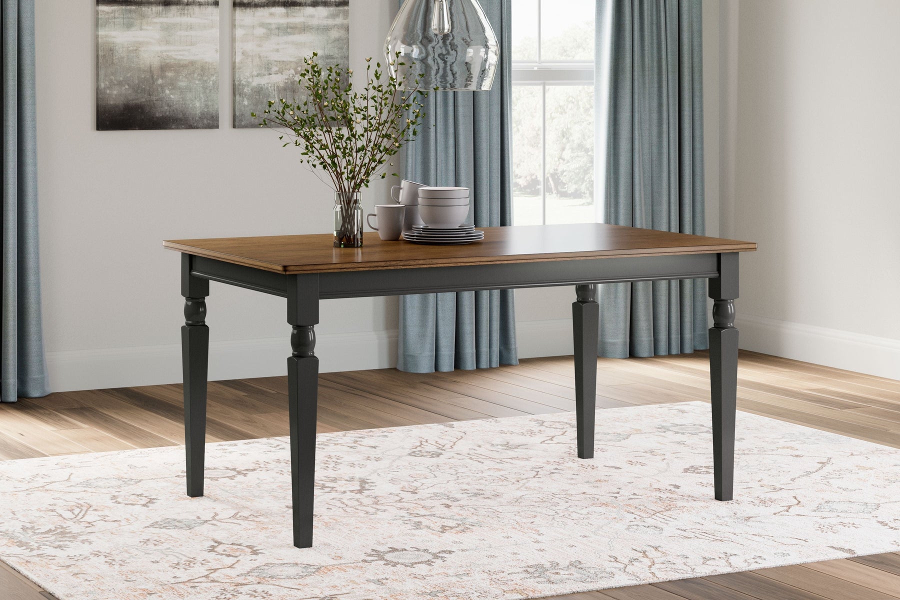 A black/brown rectangular dining room table with flowers in a vase and plates on top.