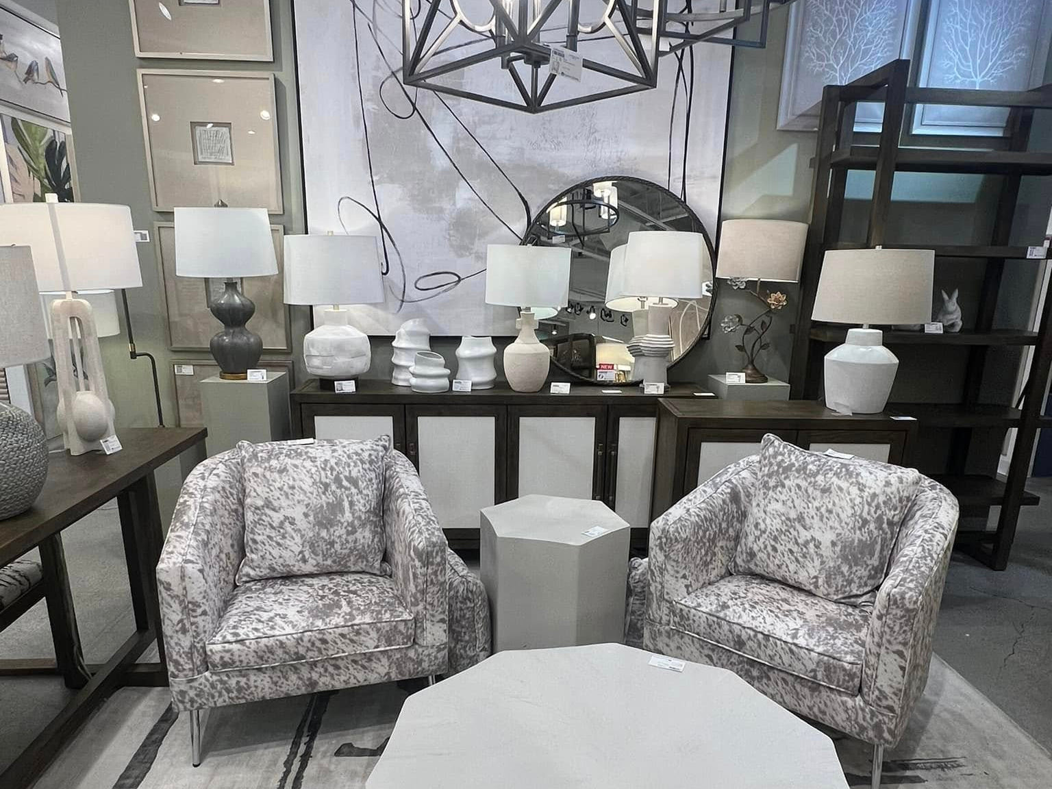Modern living room with two patterned armchairs, a geometric coffee table, and decorative lamps.